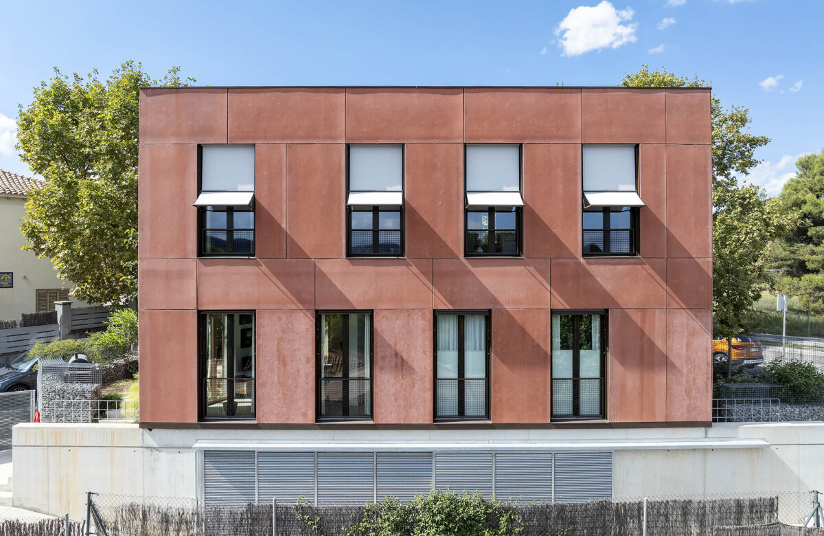 Casa Pasiva diseñada con eficiencia energética en mente, con fachada de color terracota y ventanas grandes. La construcción casa sostenible en Sant Cugat es un modelo de vivienda moderna y respetuosa con el medio ambiente