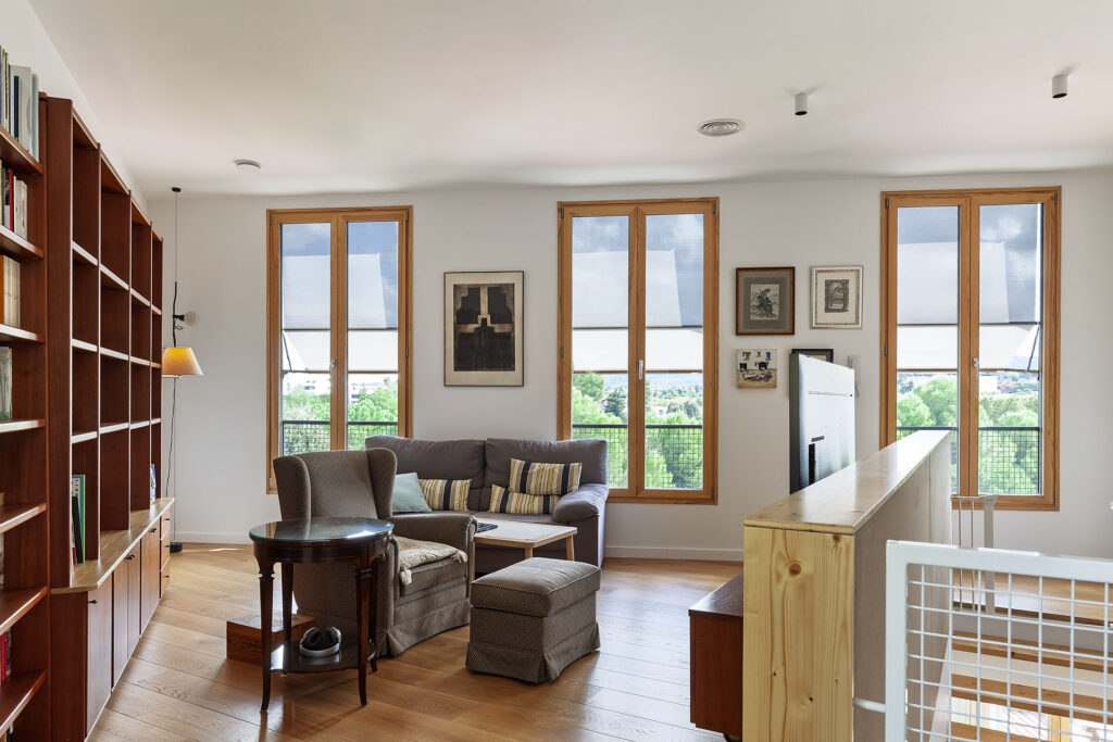 La fotografia il·lumina un espai de menjador i relaxació d'una casa passiva, dissenyada per oferir un estil còmode i durable. L'espai, equipat amb mobles de fusta natural i decoració minimalista, és ben il·luminat per llum natural, creant un ambient acollidor i tranquil. La construcció de cases passives o cases de molt alta eficiència energètica és més que una opció; és una inversió cap a un estil de vida sostenible i respectuós per l'entorn.