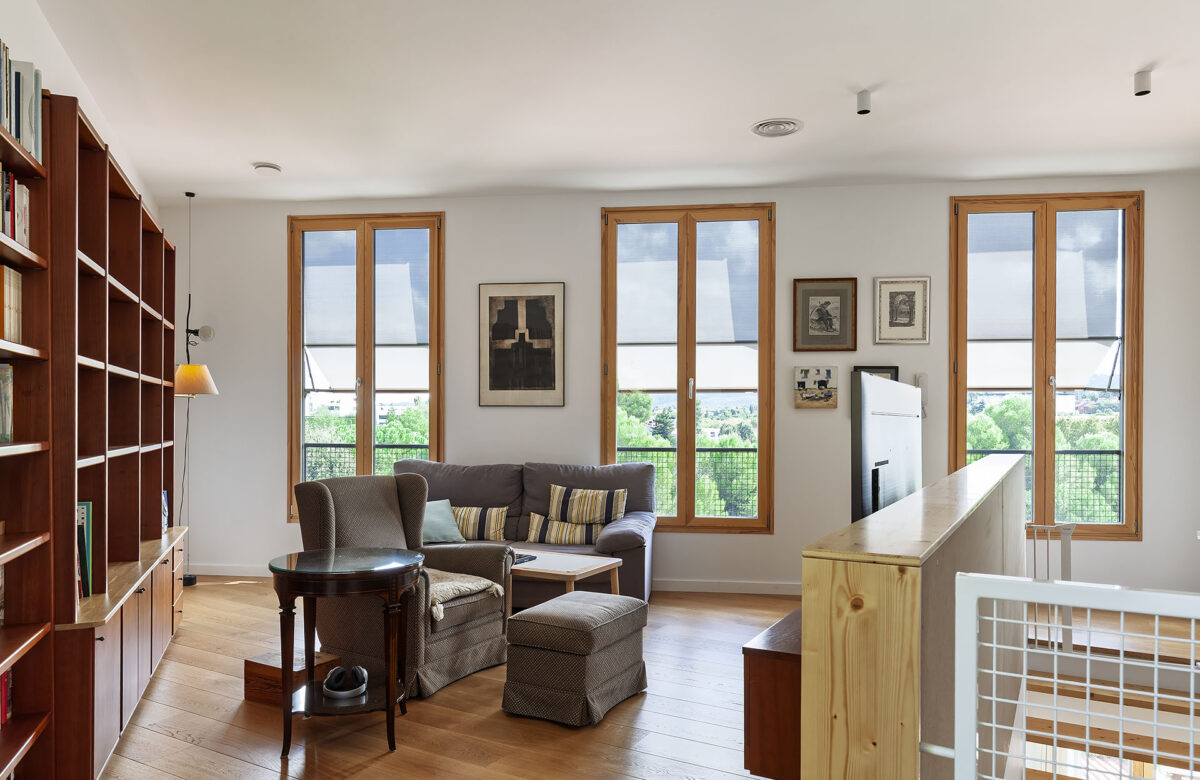 La fotografia il·lumina un espai de menjador i relaxació d'una casa passiva, dissenyada per oferir un estil còmode i durable. L'espai, equipat amb mobles de fusta natural i decoració minimalista, és ben il·luminat per llum natural, creant un ambient acollidor i tranquil. La construcció de cases passives o cases de molt alta eficiència energètica és més que una opció; és una inversió cap a un estil de vida sostenible i respectuós per l'entorn.