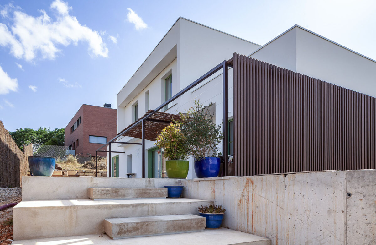 Exterior d’una casa moderna amb porxo, jardí i revestiment de fusta